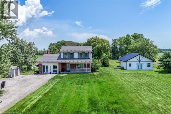Front exterior view of a two-story house with a covered porch and a separate detached garage on a grassy lawn. - 1284 Cheapside Road, Jarvis