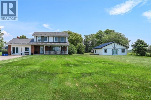 Front exterior of a two-story house and detached building, set on a wide green lawn under a blue sky. - 1284 Cheapside Road, Jarvis