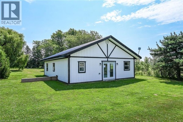 Exterior of a detached white building with black trim, featuring double doors and windows on a green lawn. - 1284 Cheapside Road, Jarvis
