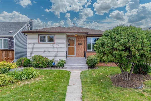 Front exterior view of a residential house with mature trees and landscaping. - 1287 Strathcona Street, Winnipeg