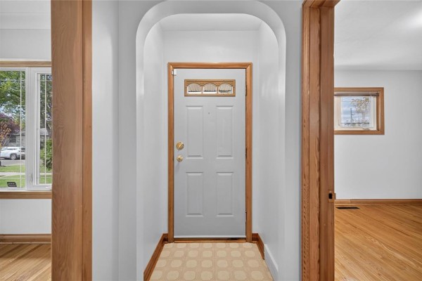 Interior view of a white front door with a glass insert, next to an archway. - 1287 Strathcona Street, Winnipeg