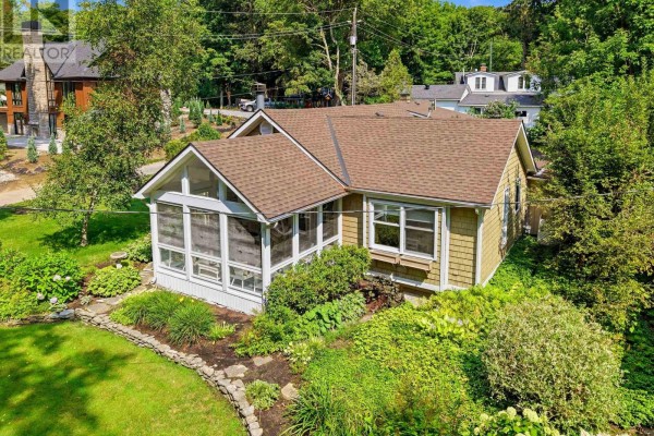 Aerial view of a bungalow with a screened-in porch surrounded by mature trees and gardens. - 1288 Walker Lane, Fort Erie
