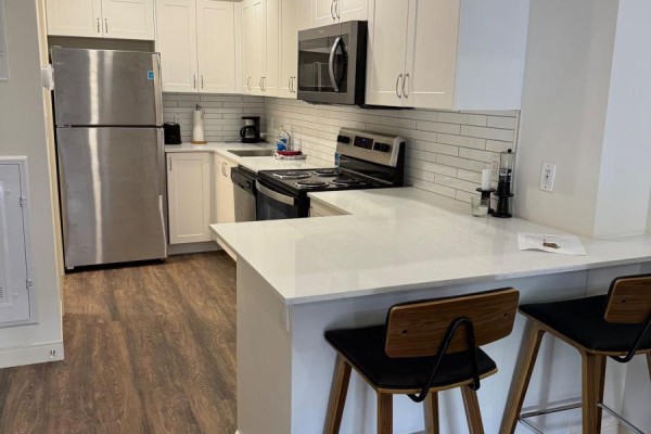 Kitchen with white shaker cabinets, white subway tile backsplash, stainless steel refrigerator, and quartz countertops. - 129 - 135 Station Street, Belleville