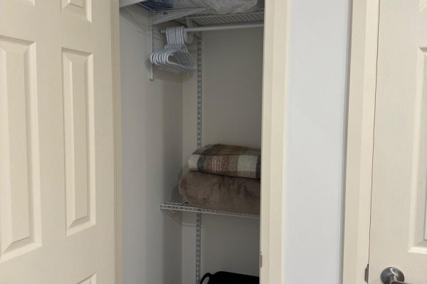 Open closet with white wire shelving, clothes hangers, and folded blankets. - 129 - 135 Station Street, Belleville