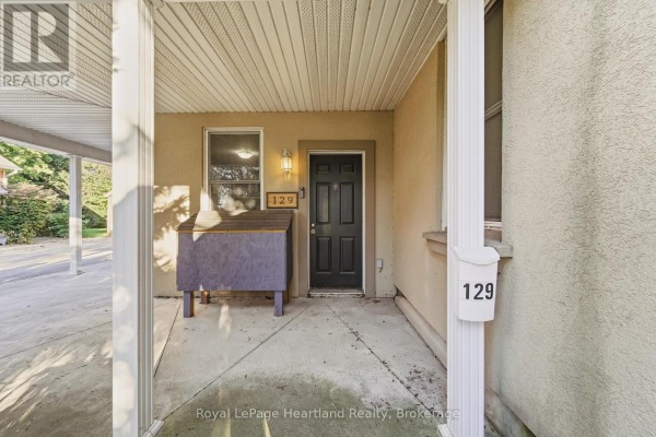 Covered porch area with a black front door, address number 129, and a purple storage bin. - 129 Bayfield Road, Goderich)