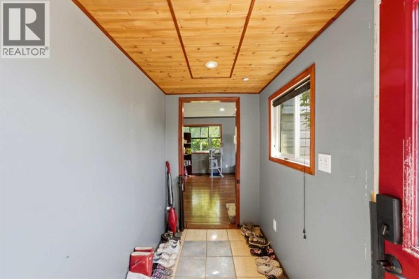 Interior view of a small entryway with gray walls, a red door, and tiled floor. - 129 Big Hill Place Se, Airdrie