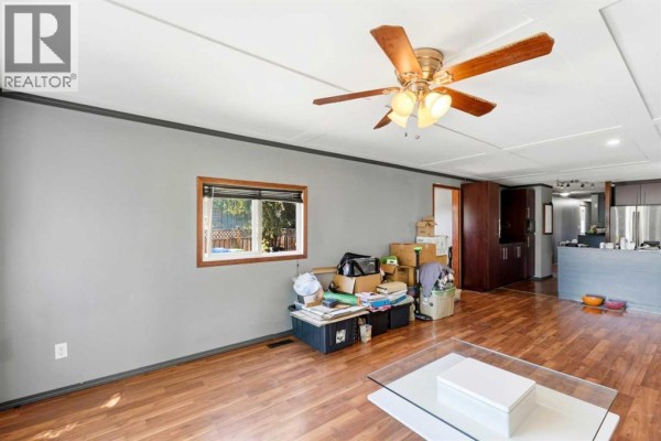 View from entryway into the main living area of the mobile home with hardwood floors. - 129 Big Hill Place Se, Airdrie