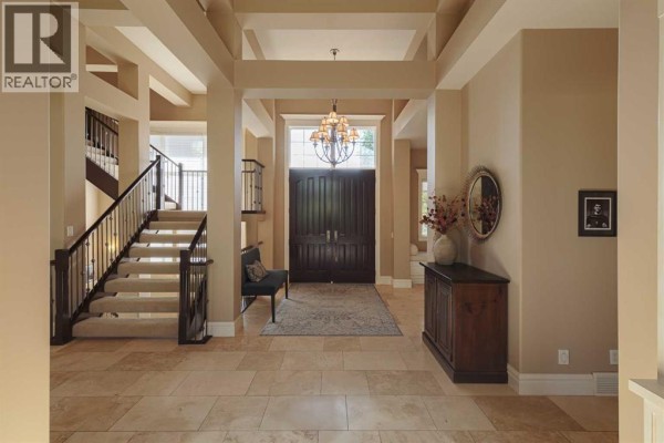 Spacious entryway with a double dark wood door, beige walls, a winding staircase with dark railings, and tiled floors. - 129 Heritage Lake Drive, Heritage Pointe