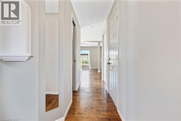 Interior hallway with dark hardwood floors, white doors, and a view into the living area. - 129 Kovac Road, Cambridge