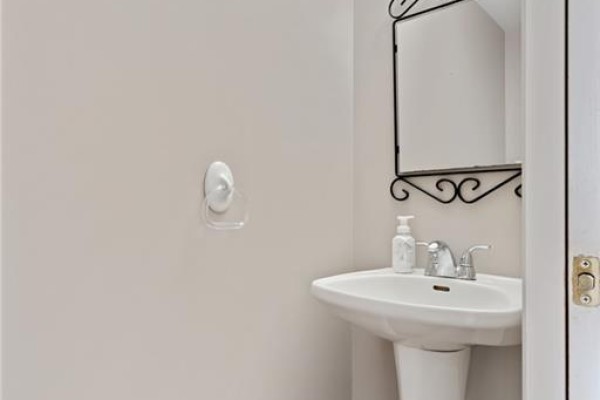 Close-up of a pedestal sink and chrome faucet in a small powder room with a decorative mirror. - 129 Kovac Road, Cambridge
