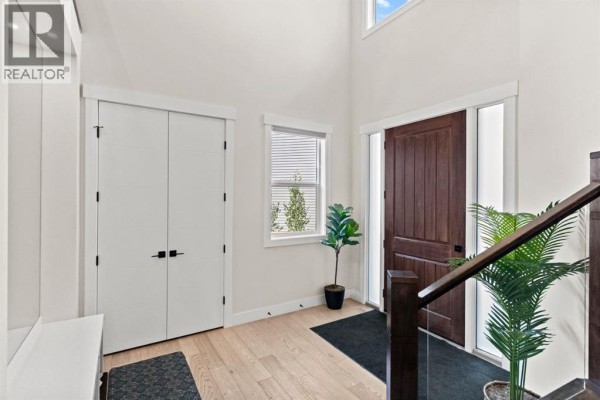 View of the entryway featuring a tall dark wood door, white shiplap accent wall, and a window. - 129 Marina Key, Chestermere