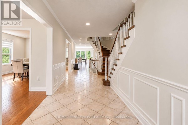 Formal dining area with a dark wood table set for six, overlooking a seating area with bay windows. - 129 Mcclellan Way, Aurora
