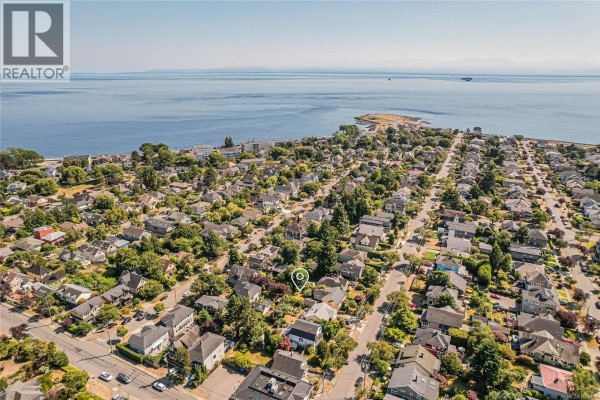 Aerial view of a Victoria neighborhood with houses and the ocean in the background. - 129 Moss St, Victoria