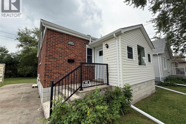Close-up of the front entrance of a brick and vinyl-sided house with stairs and railings. - 1290 Laurendeau Avenue, Windsor