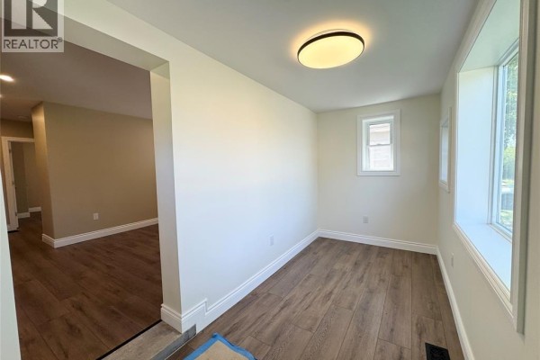 Interior room with light beige walls, vinyl plank flooring, and large windows overlooking the exterior. - 1290 Laurendeau Avenue, Windsor