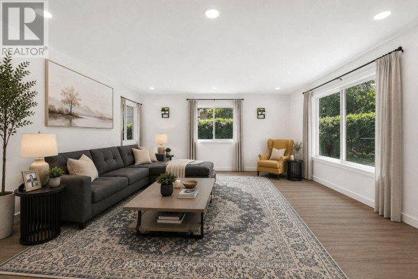 Living room featuring a charcoal sectional sofa, yellow armchair, large windows, and a patterned rug. - 1290 St. Jean Street, Ottawa