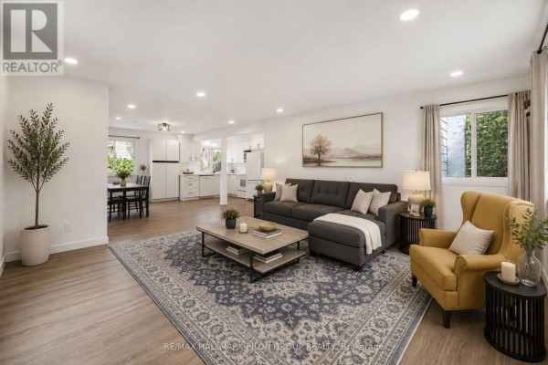 Open concept living and dining area with a white kitchen, dining table, and living room furniture. - 1290 St. Jean Street, Ottawa