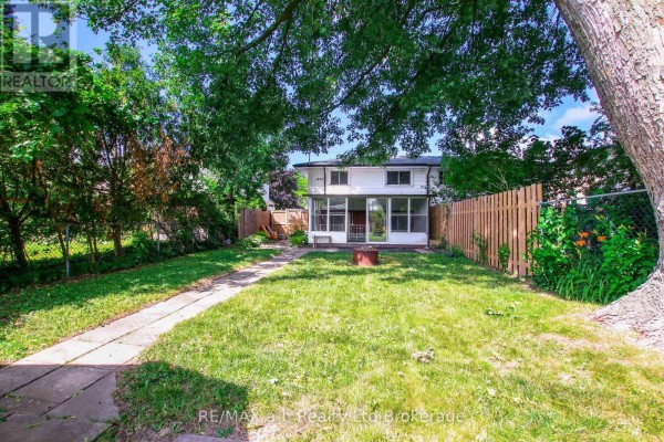 Backyard view of the house with a screened-in porch and surrounding greenery. - 1292 Sorrel Road, London East