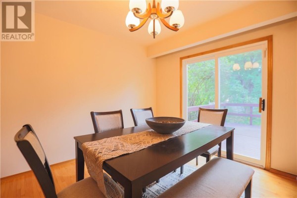 Dining room with a dark wood table, chairs, bench, and sliding glass door. - 1295 Gemmell Street, Sudbury