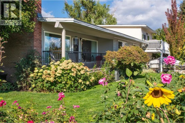 Backyard view of the duplex with a patio and lush greenery. - 1296 Kelglen Crescent, Kelowna
