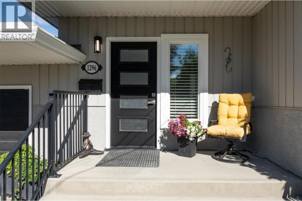Close-up of the modern front door with a yellow chair on the porch. - 1296 Kelglen Crescent, Kelowna