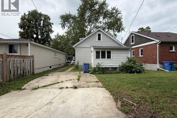 View of the side and back of the house with a narrow driveway and grassy yard. - 1296 Laurendeau Avenue, Windsor