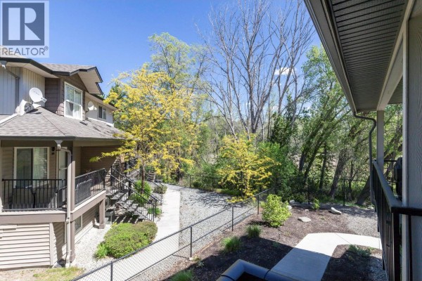 Front entrance with wooden steps, black railing, and door leading into the unit. - 1297 Findlay Road Unit# 9, Kelowna