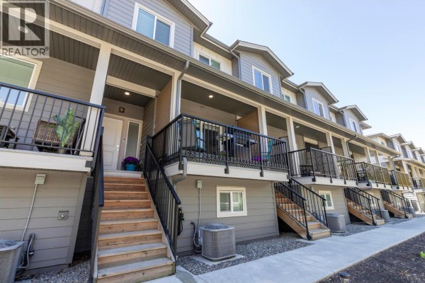 Balcony view showcasing neighboring townhouses, snow-covered landscape, and trees. - 1297 Findlay Road Unit# 9, Kelowna