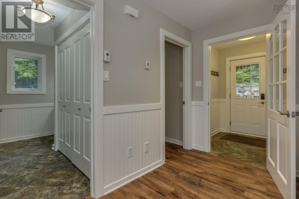 Interior hallway with wood floors, white beadboard wainscoting, and doors to various rooms. - 12991 Peggys Cove Road, Tantallon