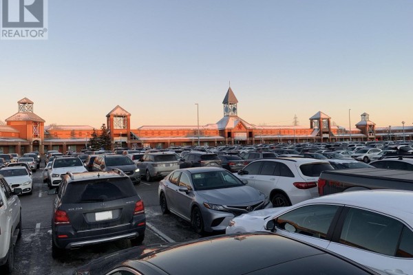 Expansive view of a shopping mall exterior with a long facade and many parked cars. - 129a - 3255 Highway 7 E, Markham