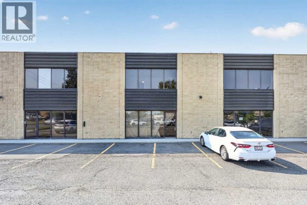 Front exterior of a commercial building with large windows and parking spaces. - 13, 4063 74 Avenue Se, Calgary