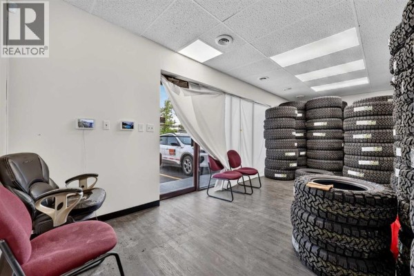 Interior waiting area with burgundy chairs and stacks of tires, overlooking an exit. - 13, 4063 74 Avenue Se, Calgary