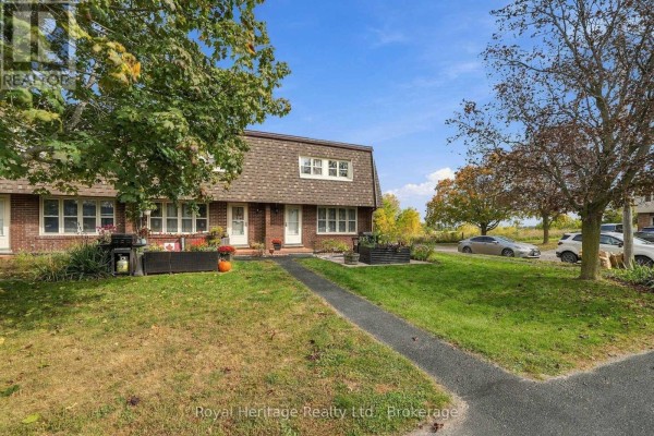 View of a brick townhouse with surrounding trees and parked cars. - 13 - 162 Cromwell Street, Trent Hills