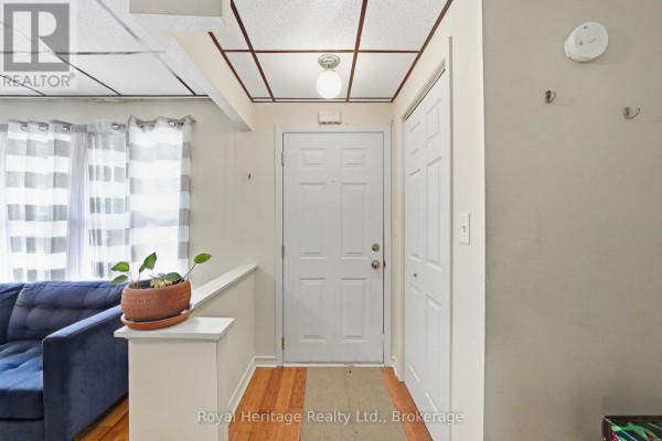 Interior hallway with white front door, closet, and navy couch. - 13 - 162 Cromwell Street, Trent Hills