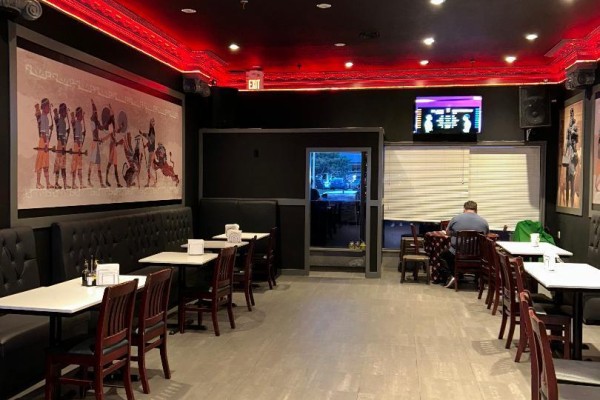 Dining tables and booths in a restaurant with a large mural and a person seated in the background. - 13 - 200 Marycroft Avenue E, Vaughan