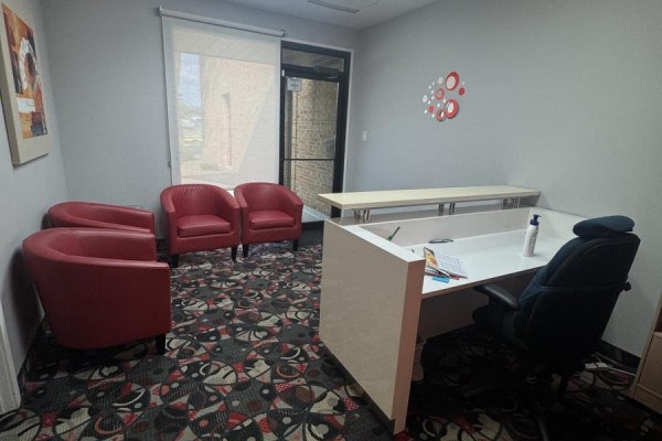 Office waiting area with red chairs, desk, and exit door. - 13 - 250 Wyecroft Road, Oakville