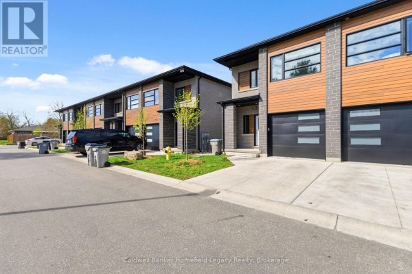 Street view of a row of townhouses with modern design, grey brick and wood accents. - 13 - 275 James Street S, St  Marys