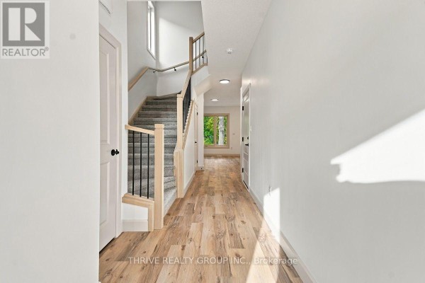 Interior hallway with light wood floors, white walls, and carpeted stairs. - 13 - 279 Hill Street, Central Elgin