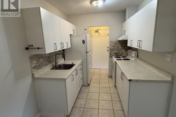 Galley kitchen with white cabinets, light grey counters, and a tiled backsplash. - 3 - 65 Race Street, Cornwall