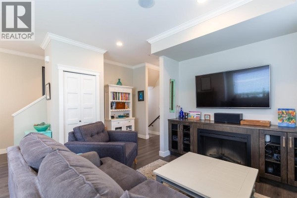 Kitchen island with dark cabinets, a double sink, and a dining area with patio doors. - 13 10480 248 Street, Maple Ridge