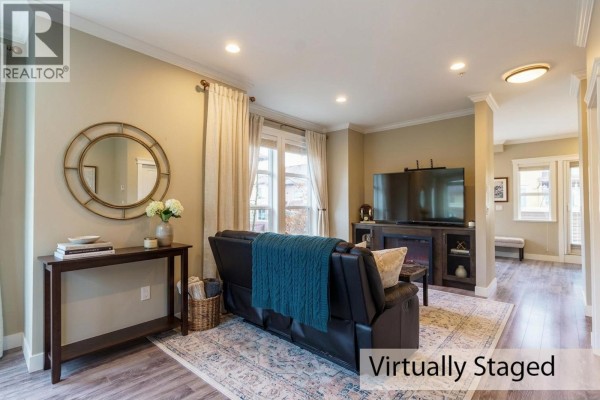 Empty living area with wall-mounted TV and natural light from windows - 13 10550 248 Street, Maple Ridge