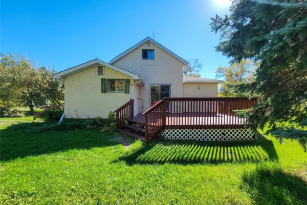 Back of the house with a sliding glass door leading to a large wooden deck. - 13 1st Street N, Eriksdale