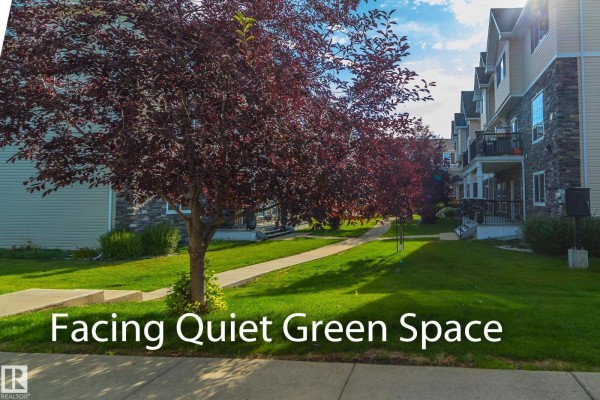 View of a paved walkway and manicured lawn in front of townhouses with trees. - #13 7289 South Terwillegar Dr Nw, Edmonton