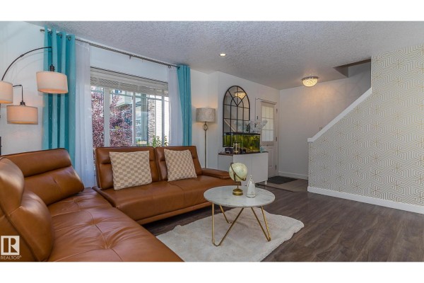 Living room with a brown sectional sofa, white rug, and decorative wallpaper. - #13 7289 South Terwillegar Dr Nw, Edmonton