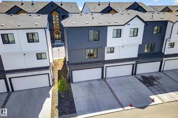 Aerial view of townhouse row with attached garages and concrete driveways. - #13 850 Secord Bv Nw, Edmonton