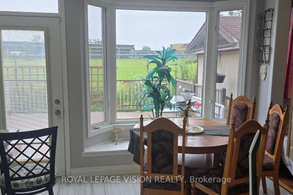 Dining area with round table near a bay window overlooking a backyard deck. - 13 Antelope Drive, Toronto