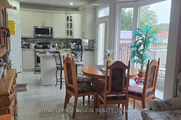 Kitchen with white cabinets, stainless steel appliances, and an island, adjacent to dining area. - 13 Antelope Drive, Toronto