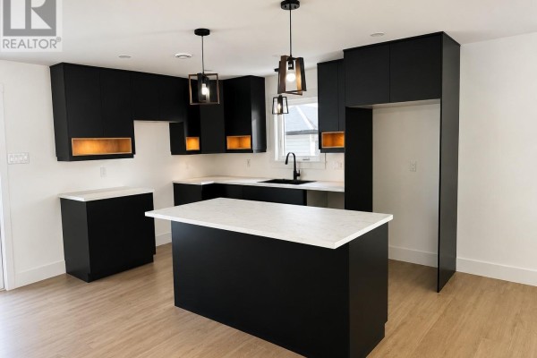 Kitchen featuring dark cabinetry, white countertops, and stainless steel appliances with a central island. - 13 Blandford Street, Gander
