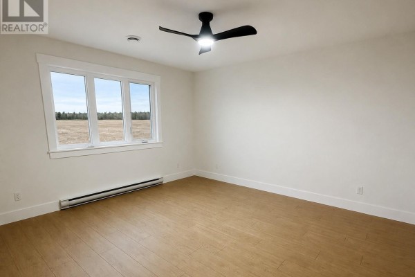 Empty bedroom with light wood flooring, a ceiling fan, and a large window overlooking construction. - 13 Blandford Street, Gander
