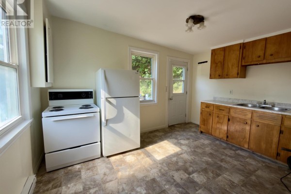 Kitchen with white stove, white refrigerator, light wood cabinets, and a back door. - 13 Chester Avenue, Kentville